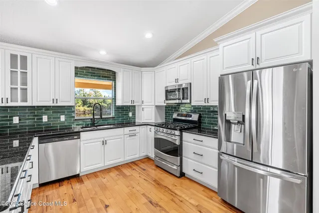 a kitchen with granite countertop a refrigerator and a stove top oven
