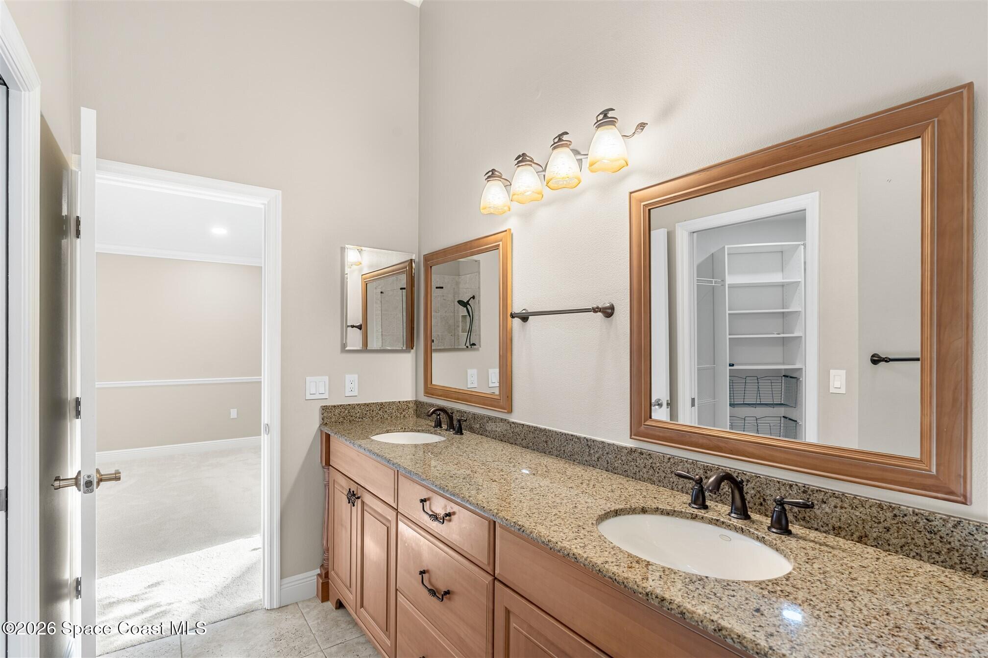 8033 Kingswood Way Melbourne, FL 32940 - Photo 34 of 70 a bathroom with a granite countertop double vanity sink a mirror and a shower