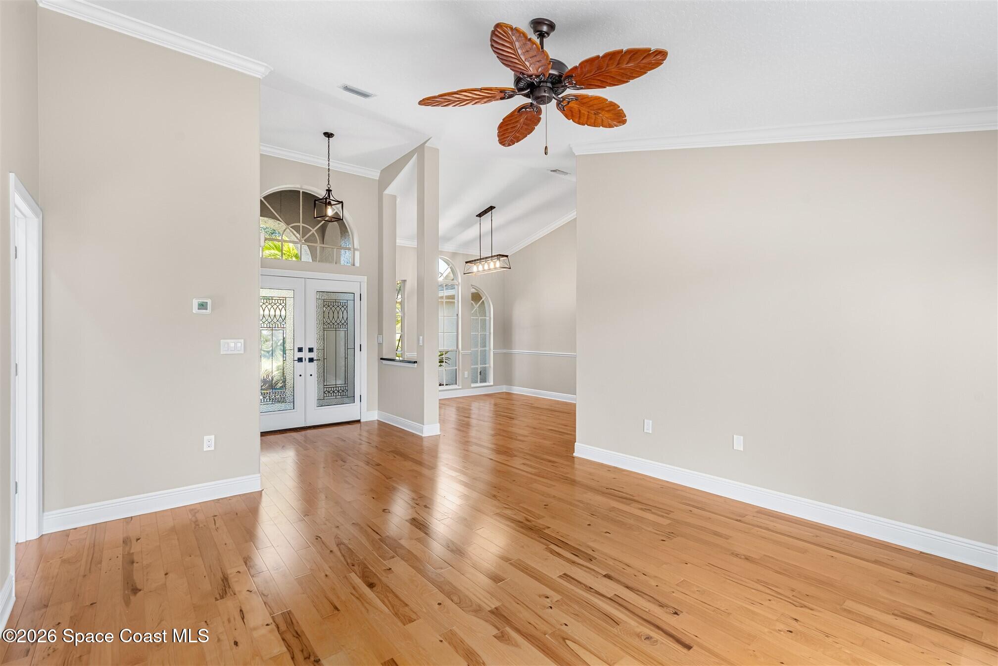 8033 Kingswood Way Melbourne, FL 32940 - Photo 9 of 70 a view of an empty room with wooden floor and a ceiling fan