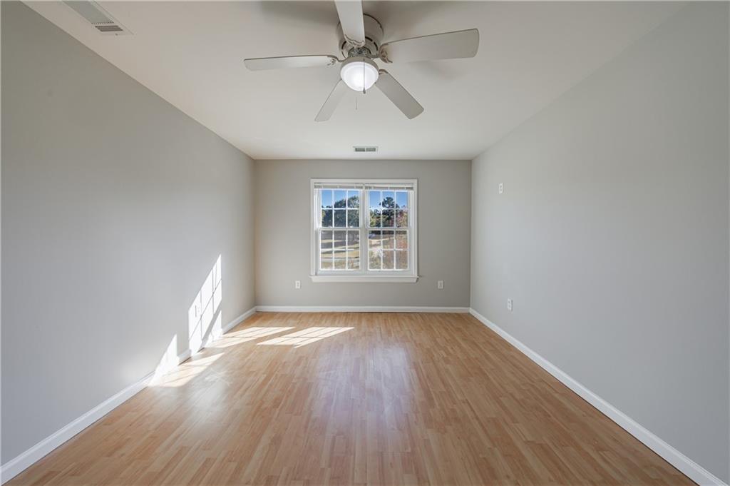 6790 Palace Lane Fairburn, GA 30213 - Photo 45 of 62 an empty room with wooden floor chandelier fan and windows