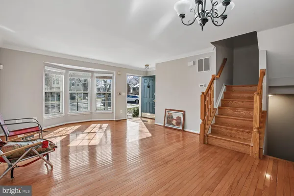 a view of an empty room with wooden floor and stairs