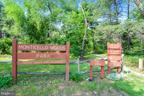 a sign that is sitting in front of a house with a big yard