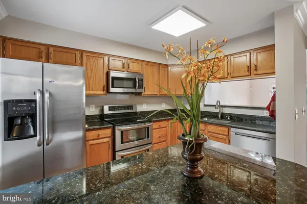 a kitchen with stainless steel appliances granite countertop a refrigerator a stove and a sink