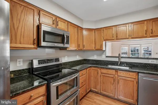 a kitchen with granite countertop cabinets stainless steel appliances a sink and a counter space