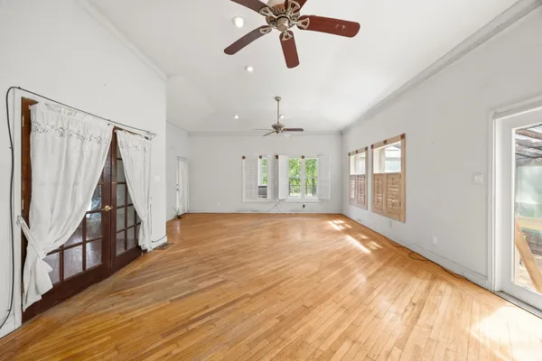 a view of an empty room with wooden floor and a window