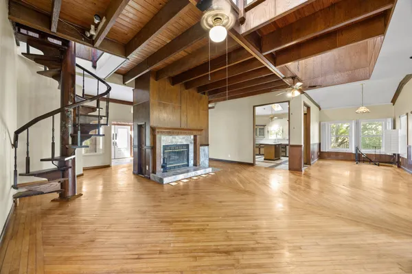 a view of an empty room with wooden floor a fireplace and a window