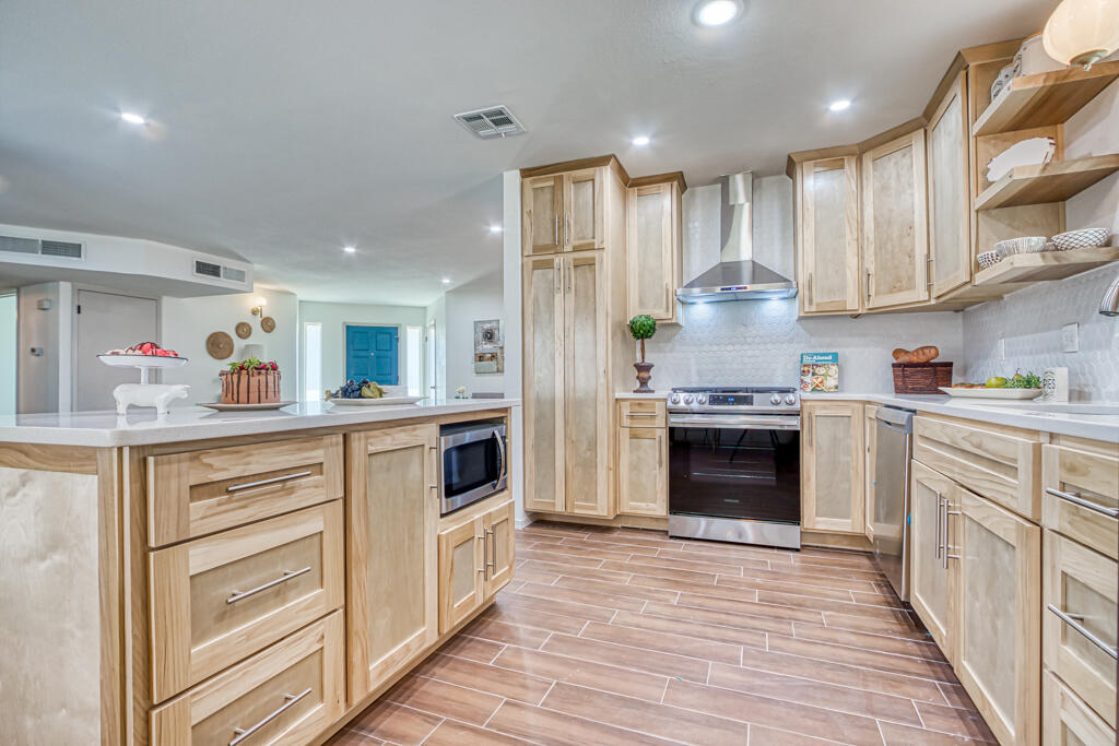 a kitchen with granite countertop a refrigerator stove and white cabinets