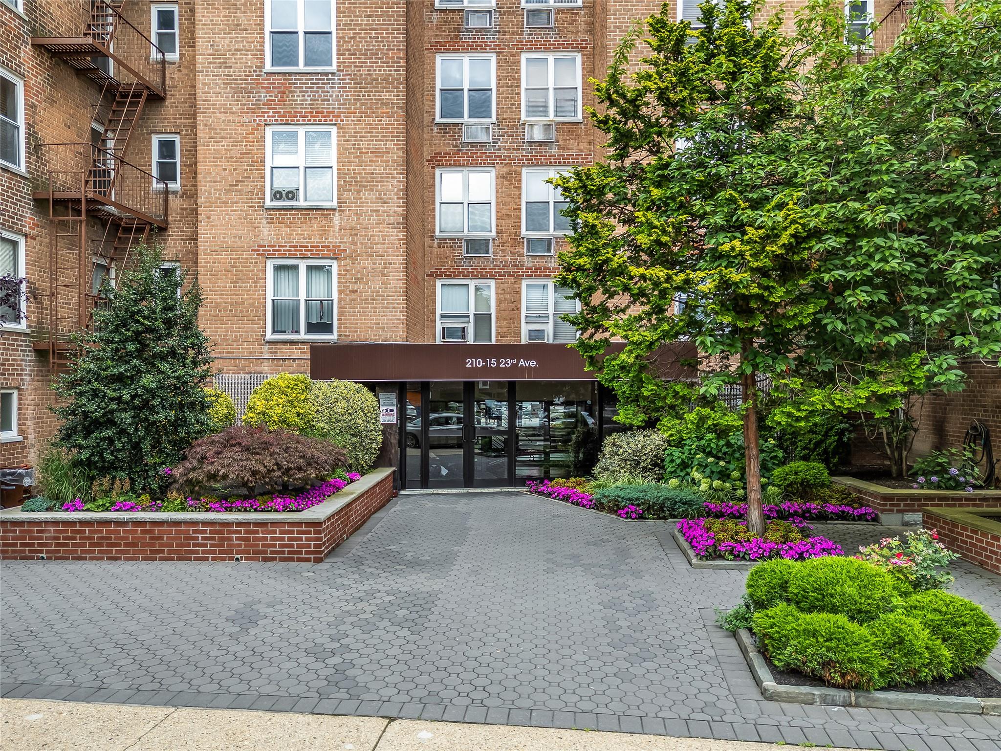 210-15 23rd Avenue, Unit 3B Queens, NY 11360 - Photo 1 of 18 a view of a brick house with a yard and potted plants