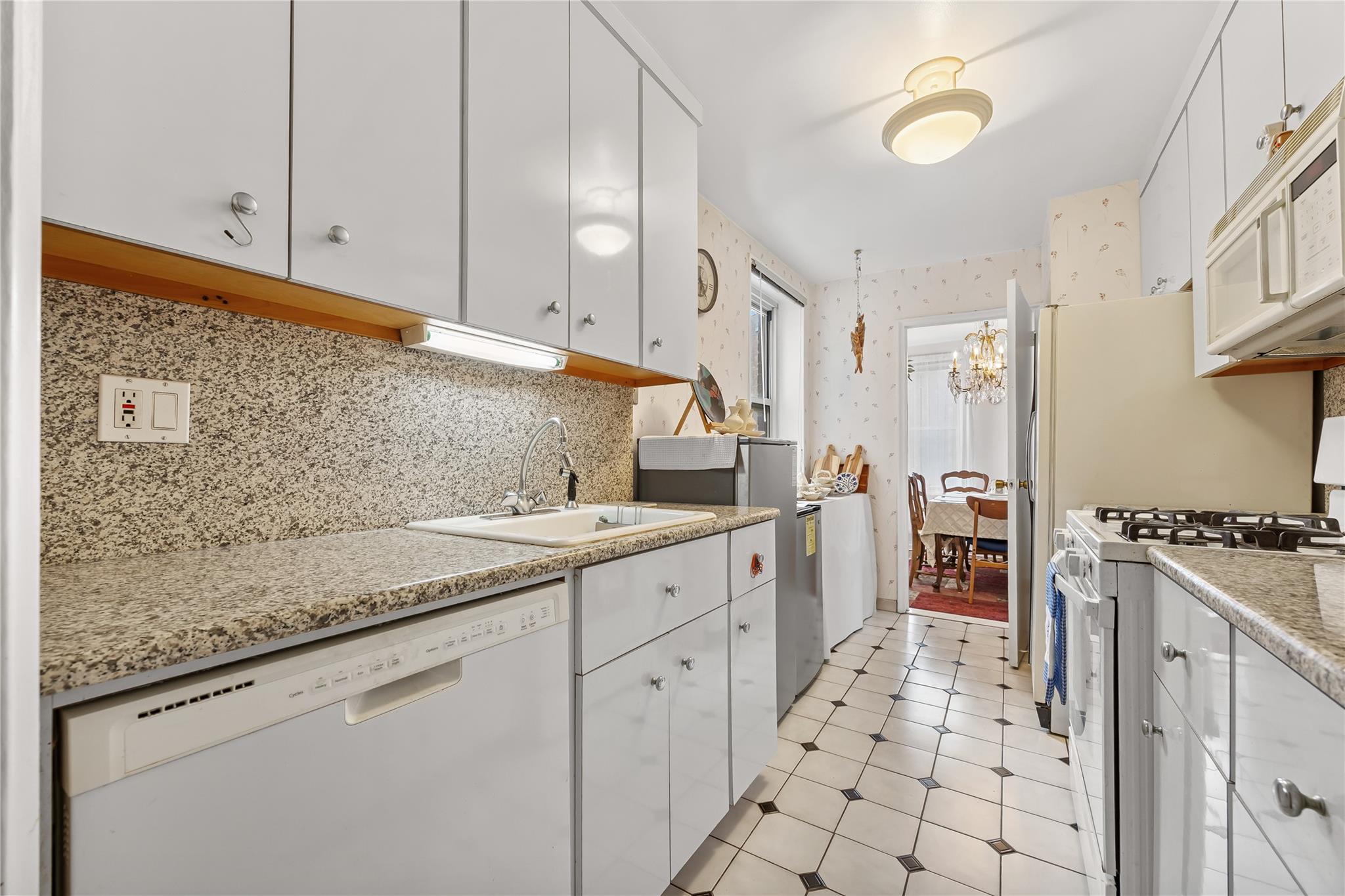 210-15 23rd Avenue, Unit 3B Queens, NY 11360 - Photo 9 of 18 a kitchen with granite countertop a sink stove and cabinets