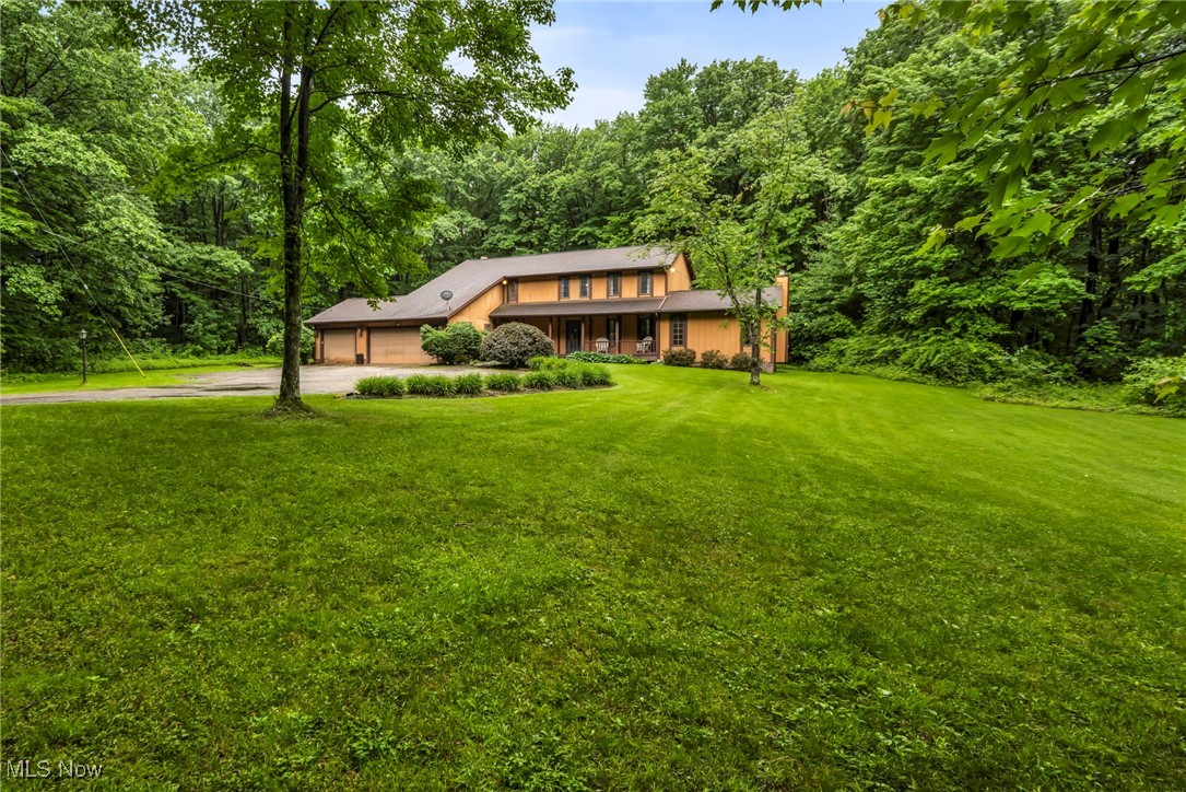 12938 Carter Road Painesville, OH 44077 - Photo 5 of 50 View of front of property with driveway, an attached garage, a front lawn, and a wooded view