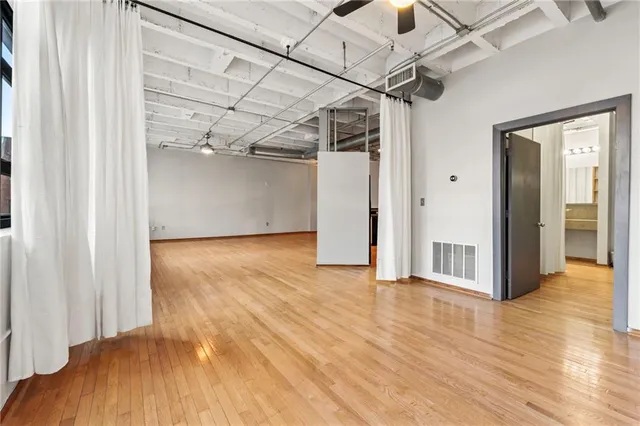 a view of a room with wooden floor a ceiling fan and windows