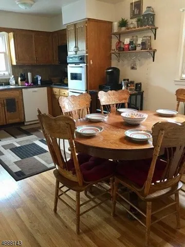 a kitchen with a stove a sink and a dining table with wooden floor