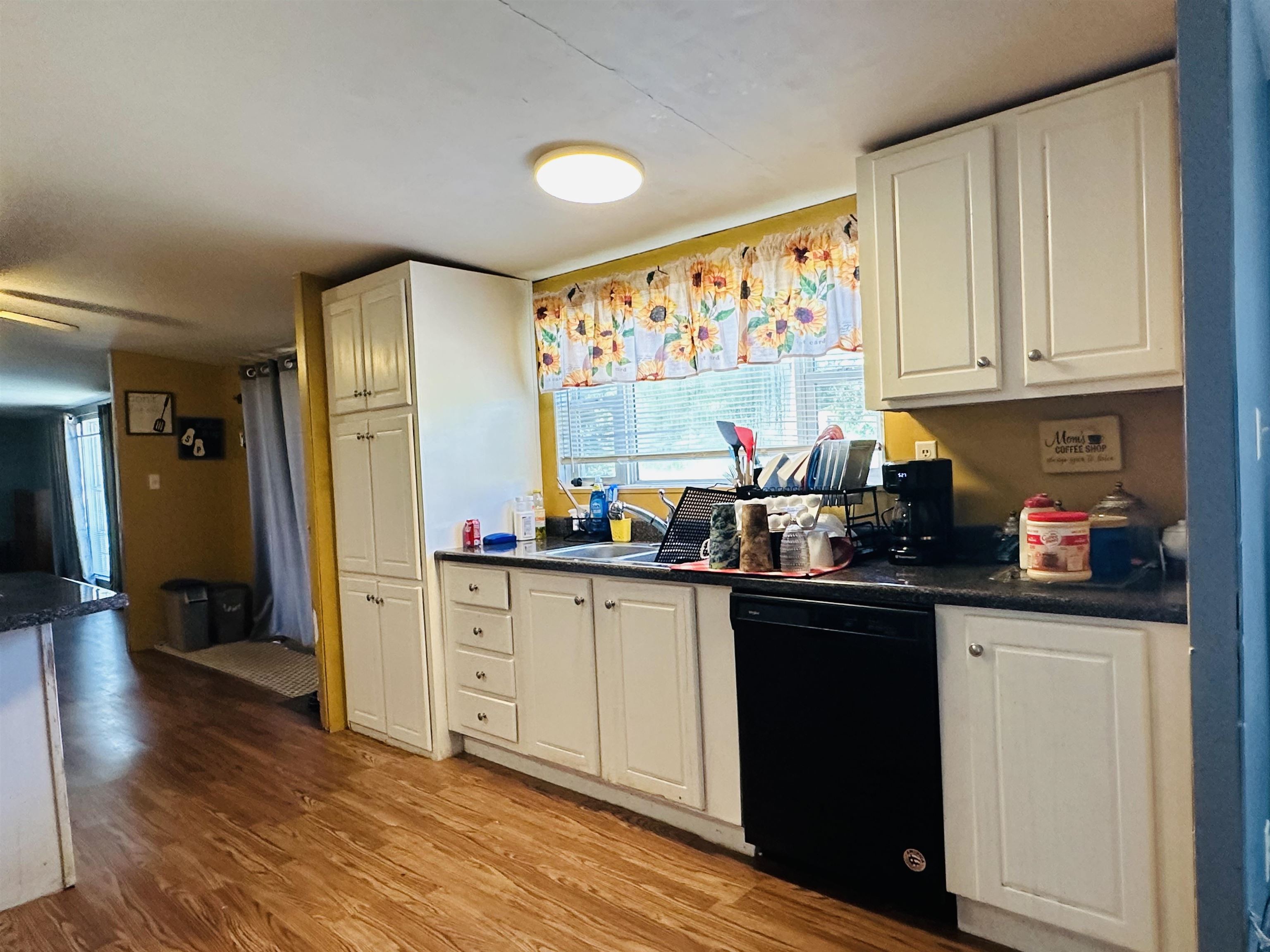 446 Gay Thompson Road Ramer, TN 38367 - Photo 8 of 30 Kitchen with black dishwasher, sink, white cabinets, and light hardwood / wood-style floors