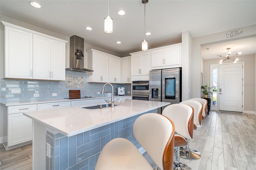 1904 146th Terrace East Parrish, FL 34219 - Photo 2 of 40 a kitchen with stainless steel appliances granite countertop a kitchen island hardwood floor sink stove dining table and chairs