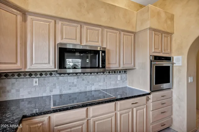 a kitchen with granite countertop white cabinets and stainless steel appliances