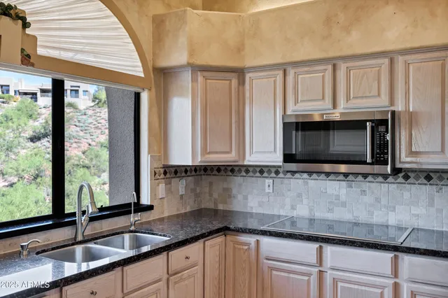 a kitchen with granite countertop a sink a window and stainless steel appliances