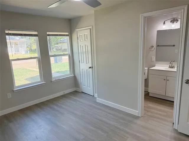 a view of an empty room with window and wooden floor