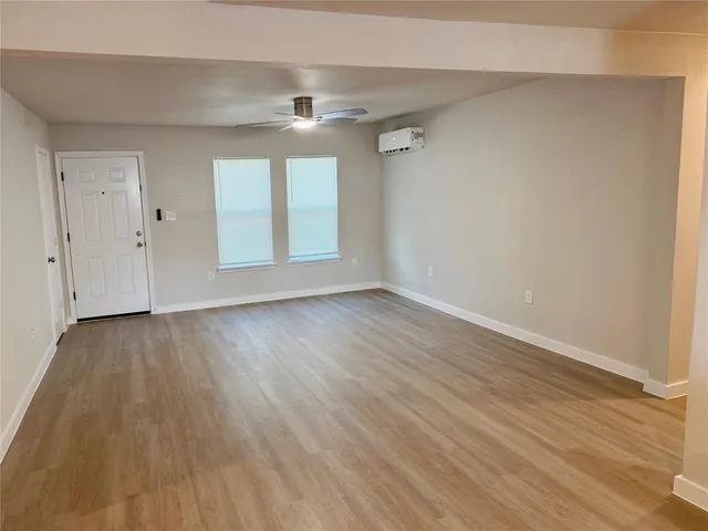 a view of an empty room with wooden floor and window