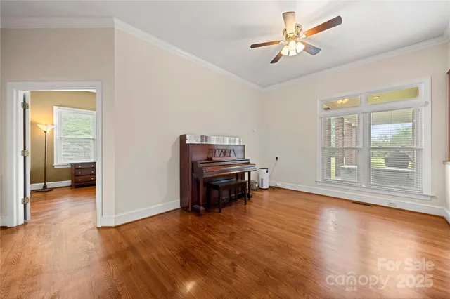 a view of empty room with wooden floor and fan