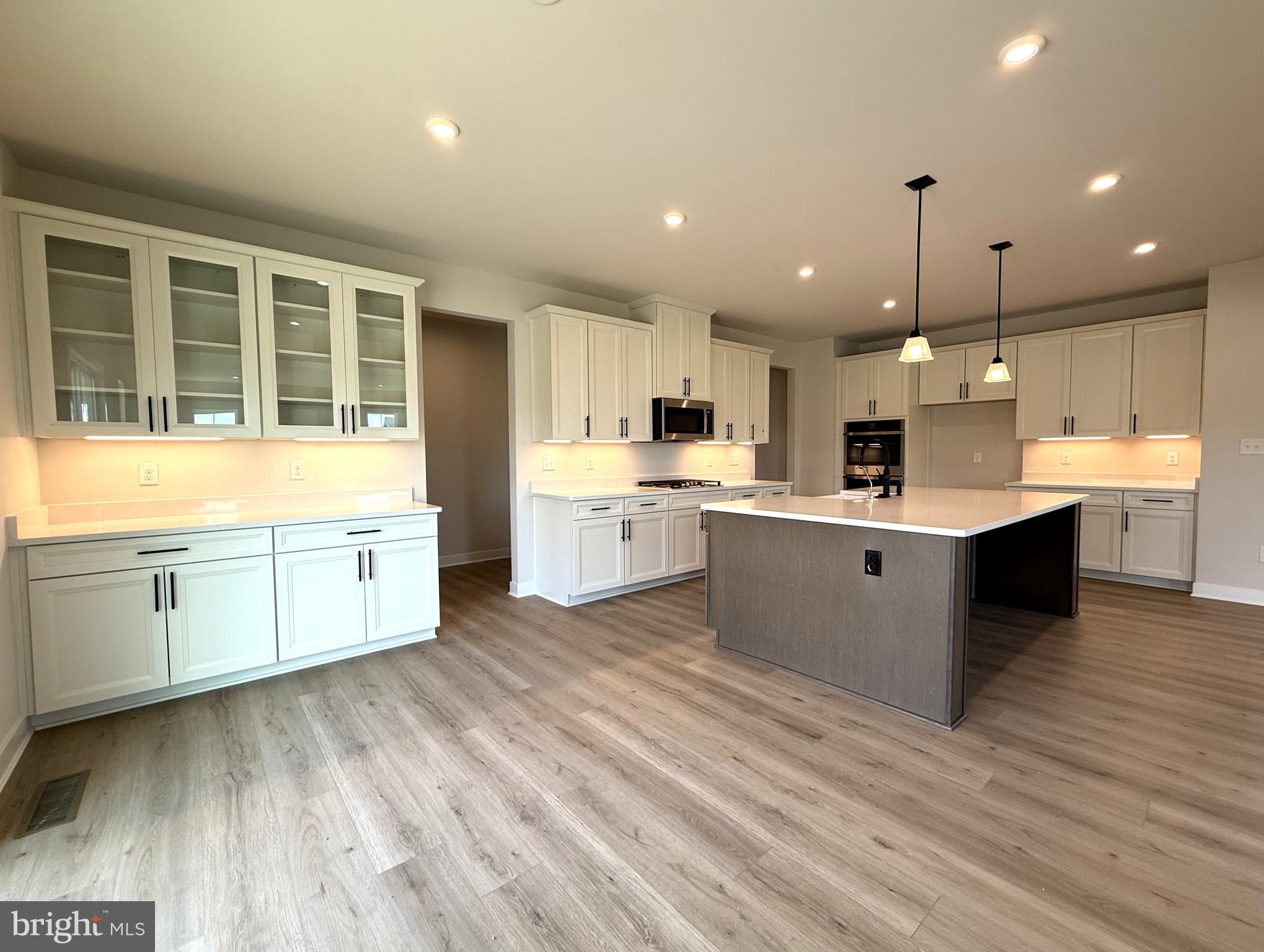 14566 Workman Circle Milton, DE 19968 - Photo 6 of 15 a large white kitchen with kitchen island a sink a stove and a wooden floors