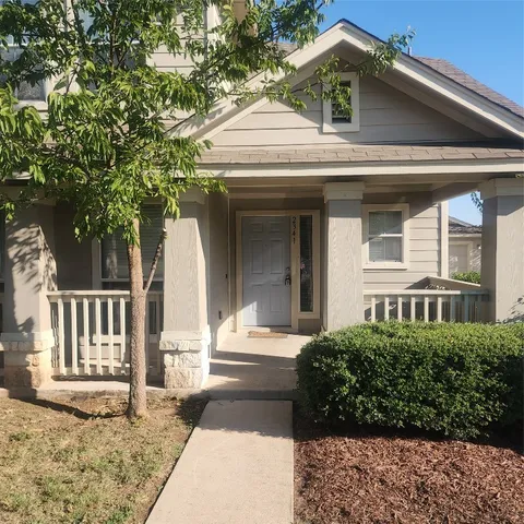 a view of a house with a small yard plants and large tree