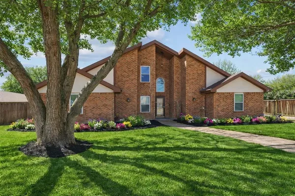 a front view of a house with a garden and trees