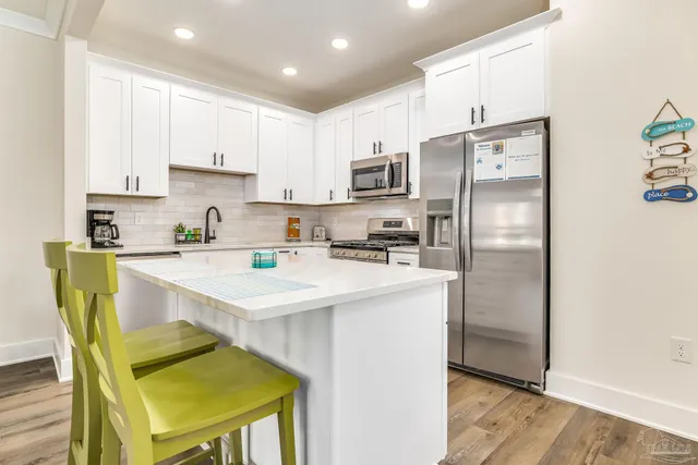 a kitchen with a stove a refrigerator and white cabinets with wooden floor