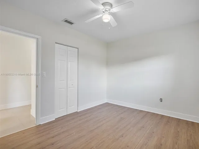 an empty room with wooden floor and fan