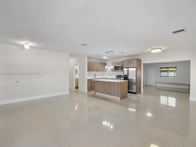a large white room with kitchen island a sink a stove and a refrigerator