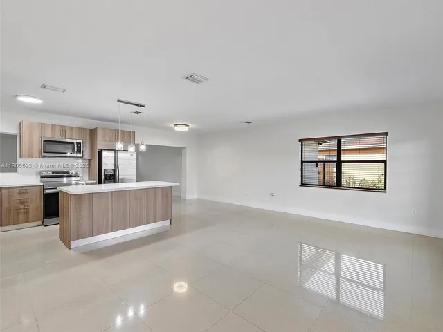 a view of kitchen with stainless steel appliances cabinets and window