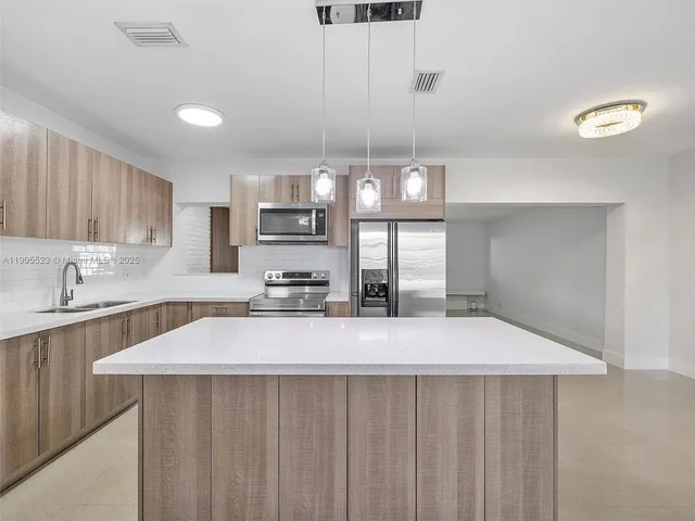 a large kitchen with kitchen island a sink stainless steel appliances and cabinets
