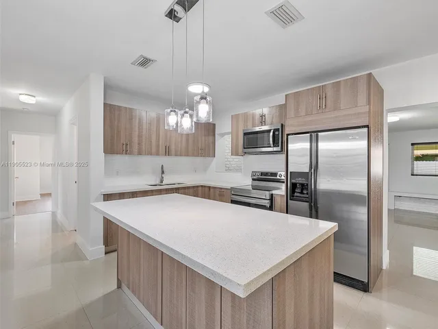 a kitchen with stainless steel appliances a table chairs refrigerator and microwave
