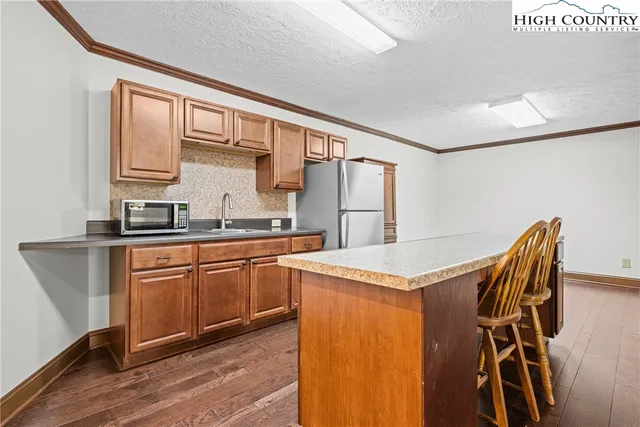 a kitchen with stainless steel appliances granite countertop a refrigerator a sink dishwasher a stove with white cabinets and wooden floor