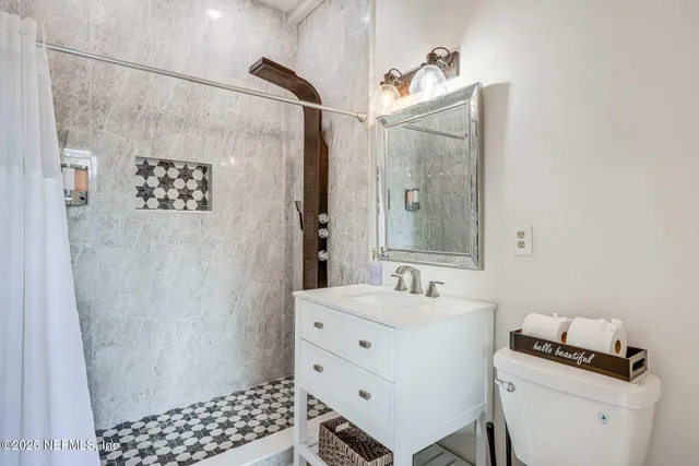 a bathroom with a sink a toilet a shower and a mirror