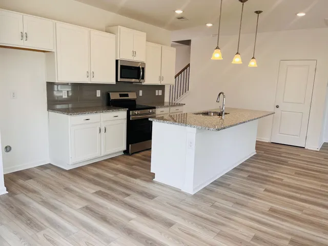 a kitchen with stainless steel appliances granite countertop a sink a stove and a wooden floors