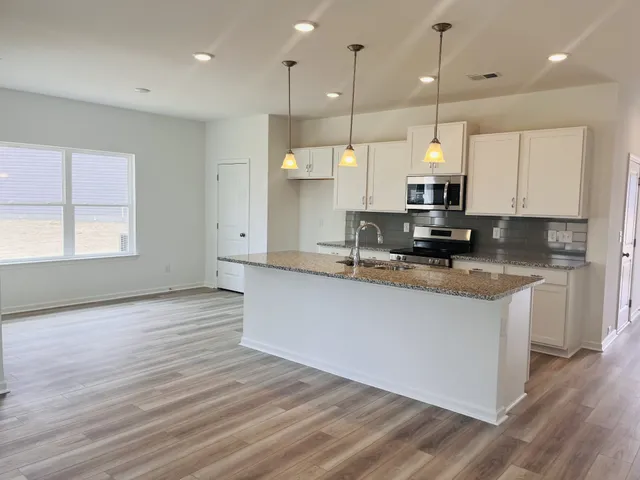 a large kitchen with stainless steel appliances granite countertop a stove a sink and a large window