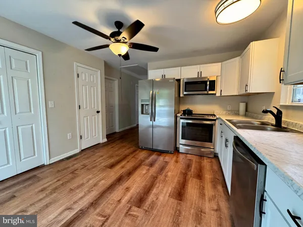 a kitchen with stainless steel appliances granite countertop a sink a stove top oven a chimney cabinets and a dining table