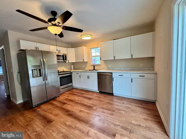 a kitchen with stainless steel appliances granite countertop a refrigerator a sink a stove a microwave oven with white cabinets