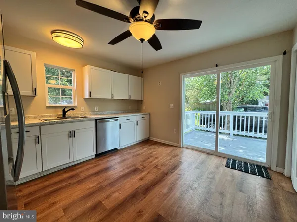a kitchen with stainless steel appliances granite countertop a stove a sink a refrigerator white cabinets and wooden floor