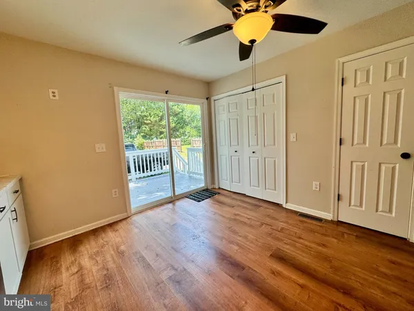 an empty room with wooden floor fan and windows