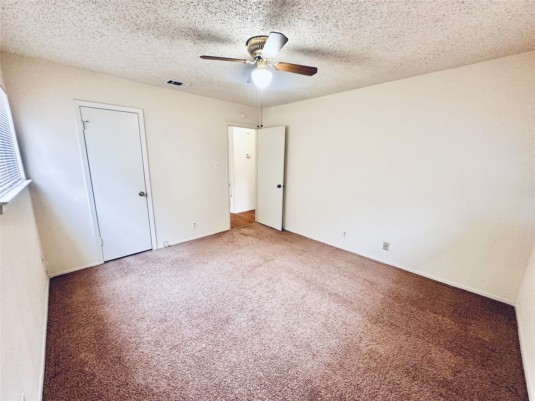 12504 Tree Line Drive, Unit B Austin, TX 78729 - Photo 16 of 22 Unfurnished bedroom with carpet, a ceiling fan, and a textured ceiling