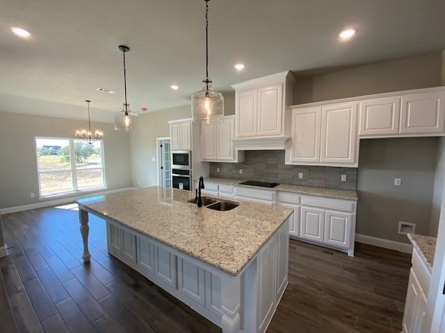 165 Coalson Crossing Azle, TX 76020 - Photo 9 of 23 a kitchen with kitchen island granite countertop wooden cabinets and white appliances