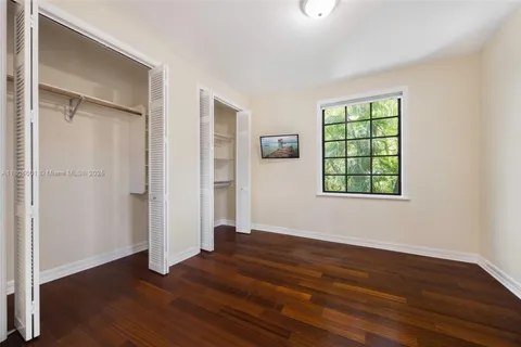 an empty room with wooden floor closet and windows