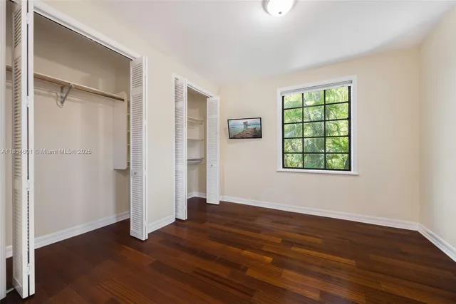 an empty room with wooden floor closet and windows