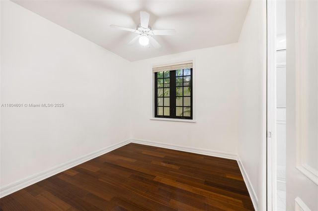 an empty room with wooden floor chandelier fan and windows