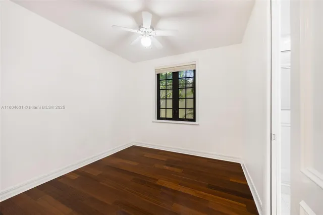 an empty room with wooden floor chandelier fan and windows