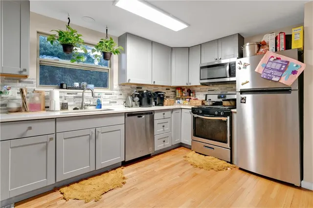 a kitchen with stainless steel appliances a sink cabinets and wooden floor
