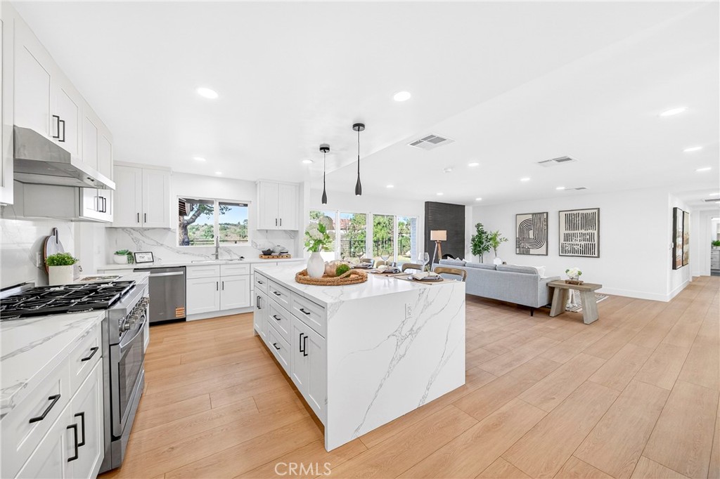 930 Rancho Circle Fullerton, CA 92835 - Photo 16 of 57 a open kitchen with stainless steel appliances kitchen island a stove a sink dishwasher and a fireplace with wooden floor