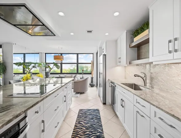 a large white kitchen with a large window and stainless steel appliances