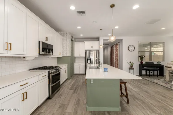 a large kitchen with kitchen island a stove a sink a refrigerator and a dining table with wooden floor